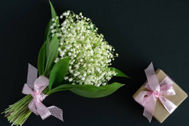 Pembe bir kurdele ve vadide bulunan güzel kokulu beyaz zambaklarla dolu bir hediye paketi. mesaj için yer. İyi bayramlar..