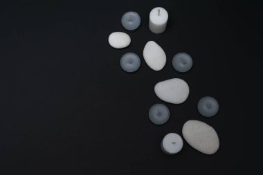 Kokulu mumlarla dolu bir spa, karanlık arka planda güzellik tedavileri için taşlar. Düzen, metin için yer. Yatay fotoğraf.