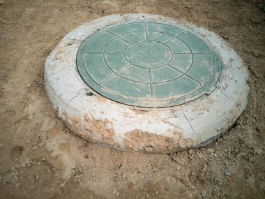 Merkez caddedeki su ve kanalizasyon şebekeleriyle bağlantılı. Bir toprak parçasında kanalizasyon kapağı. Kanalizasyon iyi. Yatay fotoğraf.