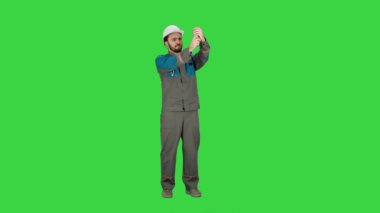 İnşaat mühendisi kask içinde üstünde a yeşil perde, Chroma Key telefonda selfie yapar.