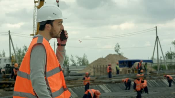 Будівельник говорить по телефону на будівельному майданчику — стокове відео