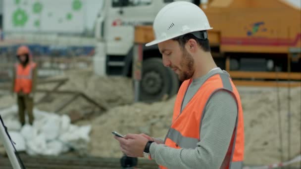 Robotnik budowlany korzystający z telefonu komórkowego — Wideo stockowe