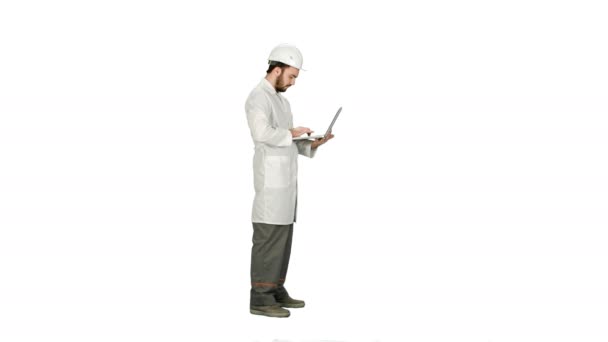 Portrait of an engineer in helmet using a laptop on white background. — Stock Video