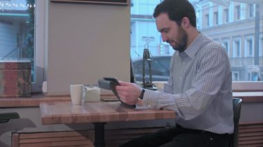 Sakallı işadamı kahve dükkanında tablet bilgisayar kullanarak