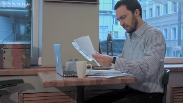 Moe jonge bebaarde zakenman in een café prepareing voor vergadering. — Stockvideo