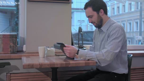 Γενειοφόρος επιχειρηματίας χρησιμοποιώντας τον υπολογιστή tablet στο καφενείο — Αρχείο Βίντεο