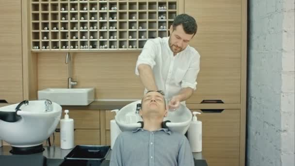 Barber mytí vlasů klienty v holičství — Stock video