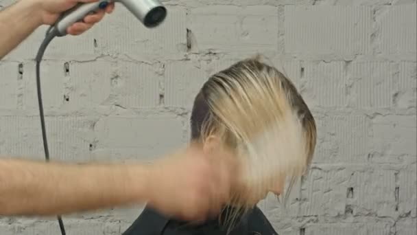 Hairdresser blowing with hairdryer womans hair at the beauty salon — Stock Video