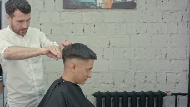 Tolle Zeit beim Friseur. fröhlicher junger bärtiger Mann lässt sich vom Friseur frisieren — Stockvideo
