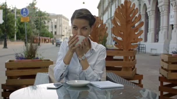 Glücklich nachdenkliche Frau trinkt in einem Café auf der Straße — Stockvideo