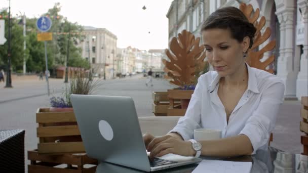Νεαρή επιχείρηση γυναίκα εργάζεται σε ένα φορητό υπολογιστή σε ένα καφέ τελειώσει τη δουλειά — Αρχείο Βίντεο