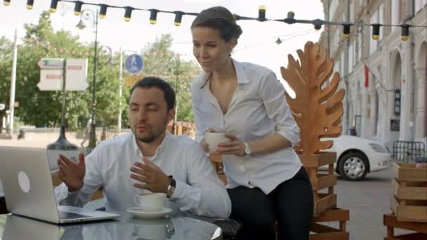 Бизнесмен и предпринимательница на видеоконференции с их коллегой в кафе — стоковое видео