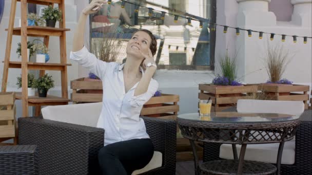 Mujer joven haciendo autorretrato usando smartphone. chica haciendo selfie. mujer en la cafetería. mujer sola. autorretrato en cafetería al aire libre. Sonríe. smilimg. Gadget. autorretrato. Pausa para el café. hora del café — Vídeos de Stock