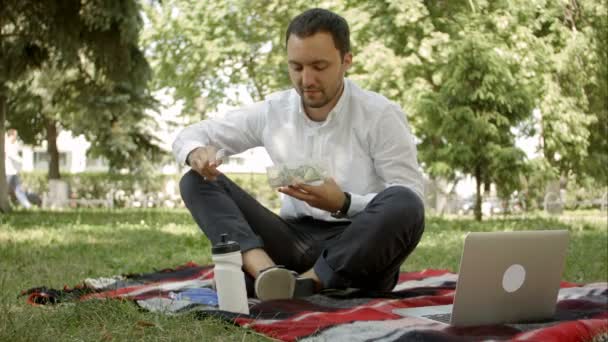 Joven hombre de negocios disfrutando de la comida que trajo en una lonchera de casa. Hora del almuerzo en el parque al aire libre . — Vídeos de Stock