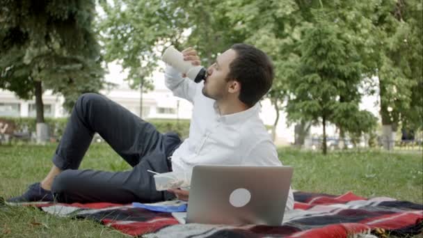 Tineri executivi care lucrează în parc pe laptop, în timp ce iau prânzul — Videoclip de stoc