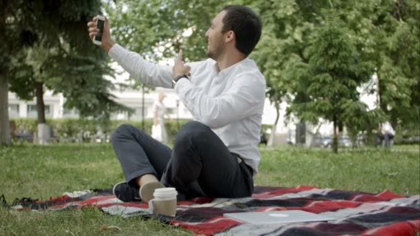 Yakışıklı adam parkta çim üzerinde oturan selfie fotoğraf yapar — Stok video