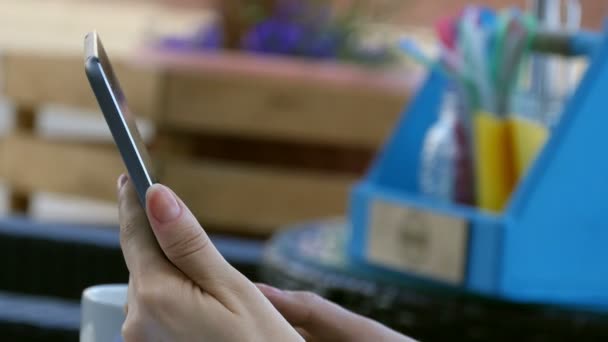 Tablet em mãos de jovem mulher agradável segurando-o e navegar na Internet enquanto descansa no café — Vídeo de Stock