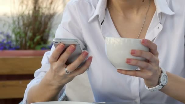 Vrouw hand met behulp van een slimme telefoon tijdens het ontbijt in cafe met koffie — Stockvideo