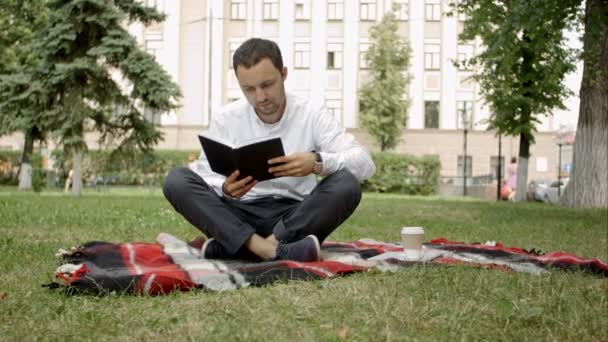 Человек, читающий книгу в парке — стоковое видео