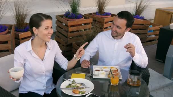 Pareja escuchando música juntos en la cafetería en un día soleado en la cafetería — Vídeos de Stock