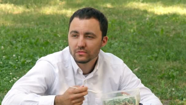 화창한 날에 아름 다운 녹색 필드에 앉아있는 남자 식 수 — 비디오