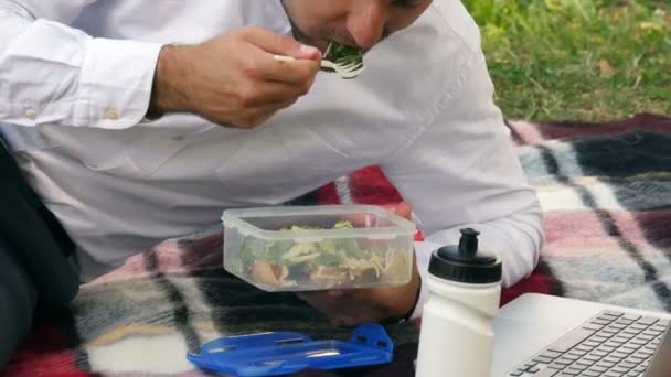 Biznesmen wsiada na zieloną trawę, jedząc obiad, — Wideo stockowe