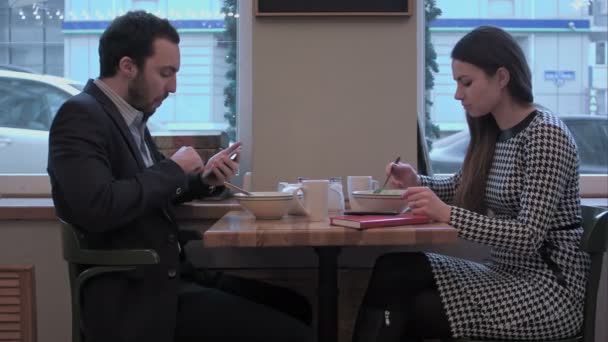 业务合作伙伴在咖啡馆享用午餐，使用智能手机 — 图库视频影像