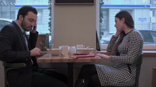 Бизнесмен и женщина общаются через смартфоны за обедом в кафе — стоковое видео