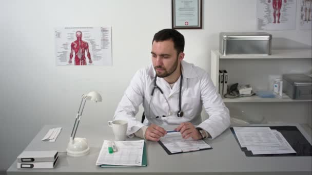 Pensando en voz alta. Médico barbudo joven reflexivo en gabinete médico . — Vídeos de Stock