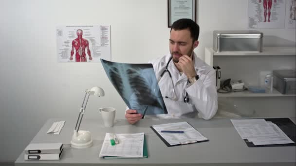 Súlyos orvos asztalnál ült, és keresi a betegek röntgen — Stock videók