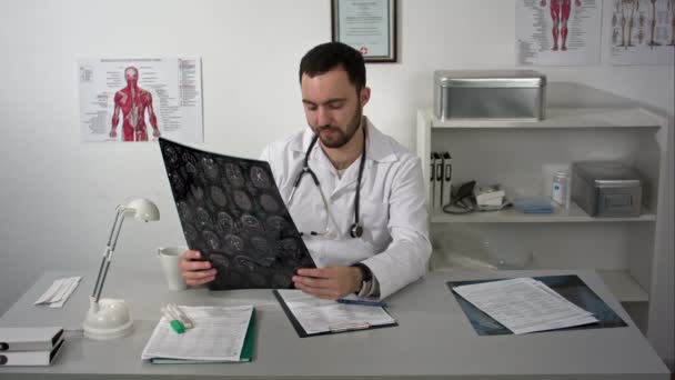Lekarz medycyny, siedząc w tabeli i pozytywnie zwiedzania pacjentów mózgu mri — Wideo stockowe