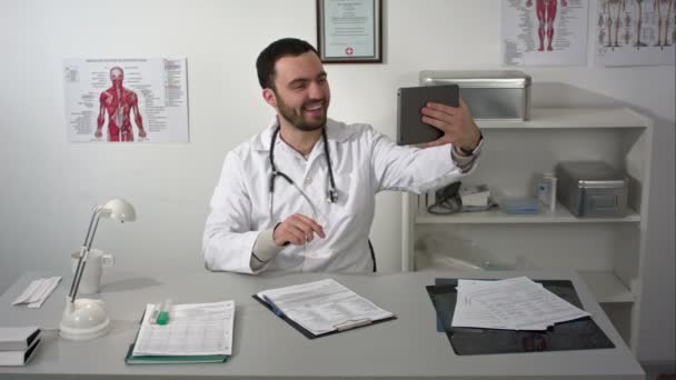 Молодий лікар приймає селфі за планшетом — стокове відео