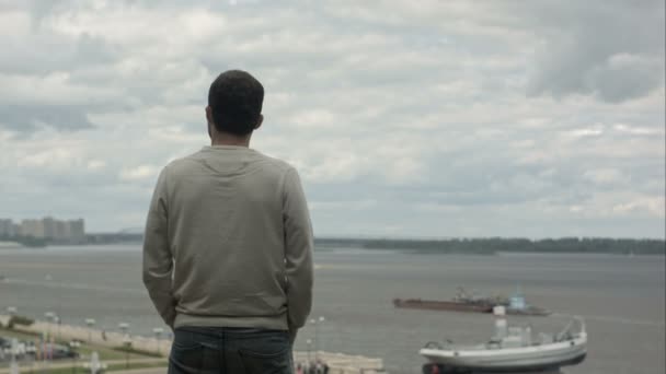 Un joven empresario está de pie junto al río, mirando hacia adelante y pensando: . — Vídeos de Stock