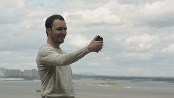 Joven tomando un montón de selfie con teléfono móvil cerca del río . — Vídeos de Stock