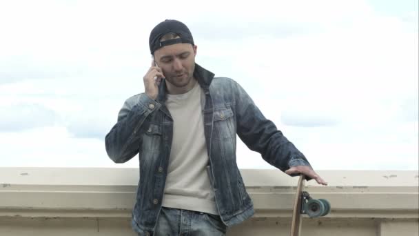 Skateboarder debout en plein air et téléphone parlant  . — Video