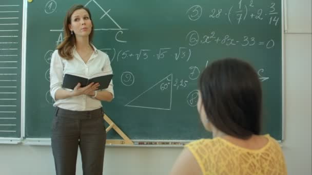 Enseignant ou docent ou éducateur donnant pendant la leçon devant un tableau ou un tableau une feuille de papier et éduquant ou enseignant des élèves ou des élèves ou des camarades dans une école ou une classe — Video