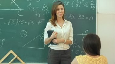 Öğretmen sınıfta yeşil kara tahta üzerinde matematik görev hakkında konuşmak gülümse
