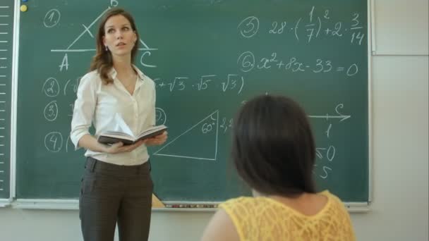 Привлекательная молодая учительница по математике, стоящая перед доской и обсуждающая — стоковое видео