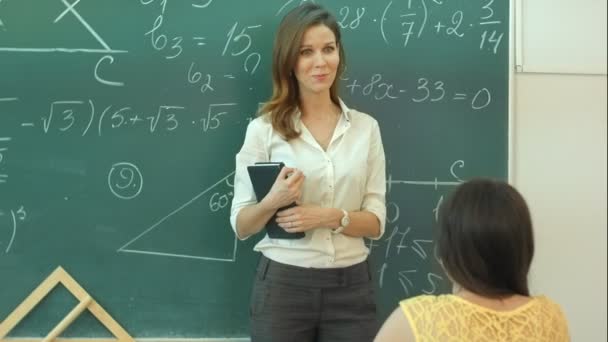 Úsměv učitel mluví o matematický úkol na zelené tabule v učebně — Stock video