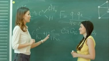 genç ve güzel Bayan üniversite öğrencisi bir kimya dersinde kara tahta tahtaya yazma