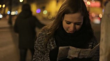 Kadın el haritasında bir şey arıyor ve etrafa bakıyor