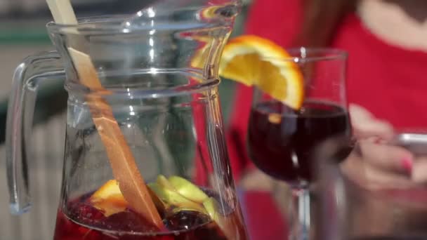 Dekanter se sangrií a sklenicemi červeného vína s oranžovým — Stock video