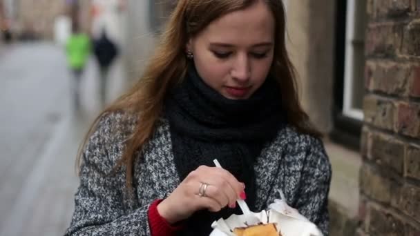 Retrato urbano de una joven y hermosa turista comiendo gofres belgas en la calle de Brujas, Bélgica . — Vídeo de stock