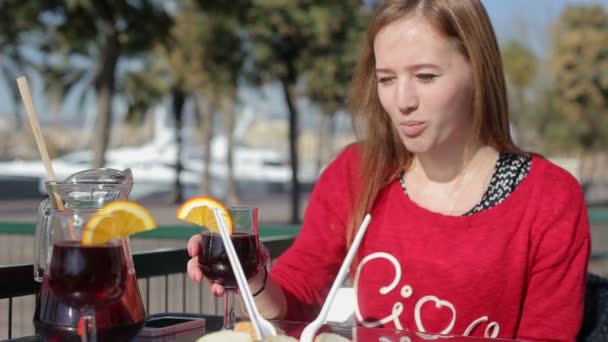 Joven hembra comiendo con vaso de asngria sola en un café de la calle . — Vídeos de Stock