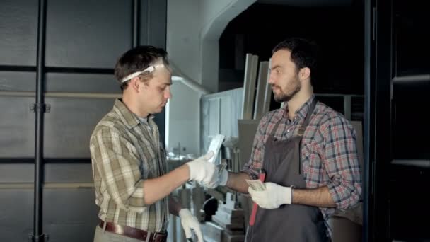 Zwei Arbeiter zählen Geld in Werkstatt. — Stockvideo