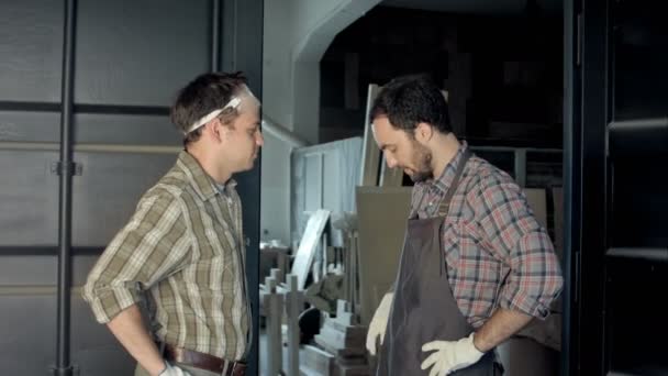 Два рабочих говорят и считают деньги в мастерской . — стоковое видео