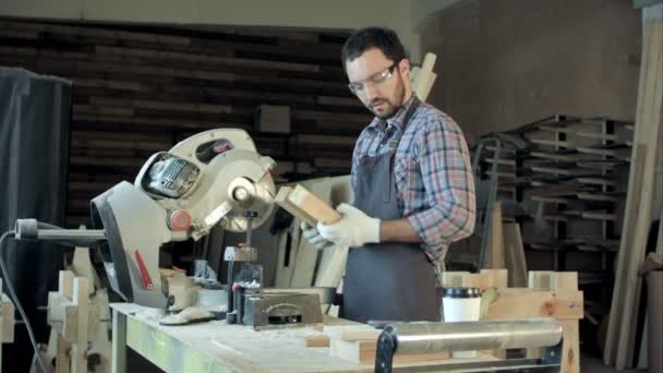 Confident young male carpenter working with wood in his workshop — Stock Video