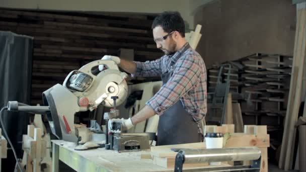 Sakallı genç marangoz bir tahta kesmek için elektrikli testere kullanarak — Stok video