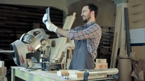 Carpenter makes selfie near woodworking machines in carpentry shop. — Stock Video