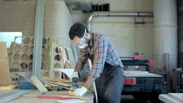 Γενειοφόρος ξυλουργός στα προστατευτικά γυαλιά εργασίας με ηλεκτρική πλάνη στο εργαστήριο. — Αρχείο Βίντεο